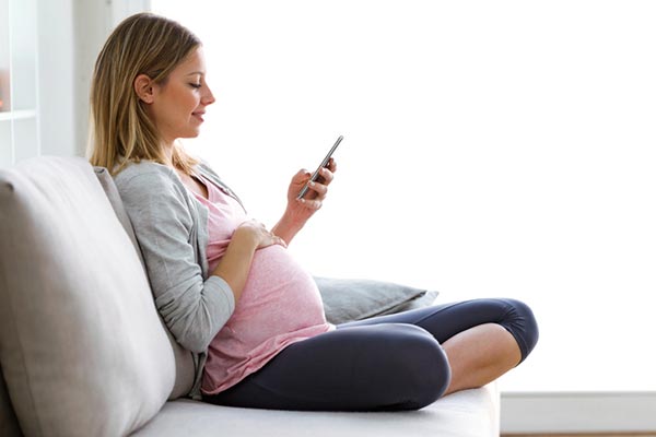 pregnant woman sitting on couch looking at phone wondering about adoption
